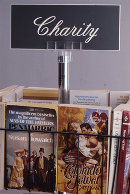 LIBRARY PERSONA NON GRATA<br />
1993<br />
Detail: romance novels<br />
romance novels in stand, Charity identification sign<br />