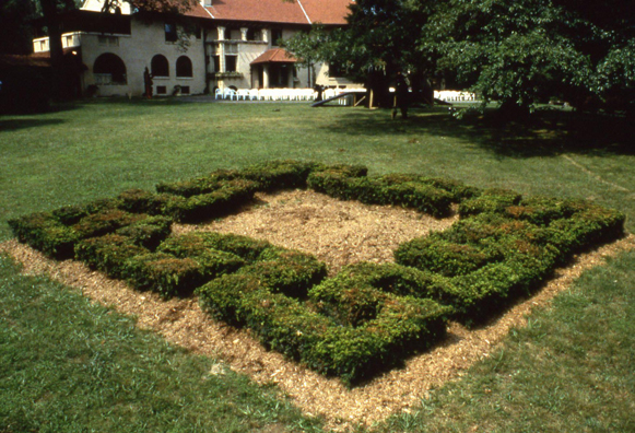 MIANDROS <br/>
1994 Ongoing <br/>
80 Dogwood Bushes Planted in a “Miandros” Greek Key Pattern and Arranged in an Unopened Square Maze, Surrounding the Solution Mound <br/>
Height of Dogwood Is Easily Seen, Walked, or Jumped over by Viewers <br/>
Dogwood Maze Left to Be Consumed by Deer, Creating the Unsolvable Maze's Entrance<br/>
Maze: 20' x 20' x 2 1/2' <br/>
Observation Mound: 5' at Highest Point <br/>