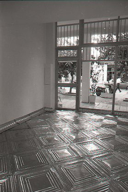ONCE UPON A TIME... ICE BOX<br />
1994 Ongoing<br />
Posterior View<br />
Floor: American Prest-Plate Ceiling Tin Installed On Top of Gallery Floor Left for Viewers to Destroy through Abrasion with Actual Gallery Floor, Viewer Imprints,<br />
Tracks, and Traffic<br />
Variable Dimensions<br />