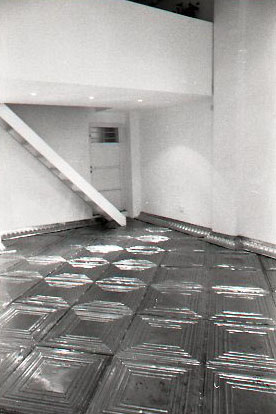 ONCE UPON A TIME... ICE BOX<br />
1994 Ongoing<br />
Anterior View<br />
Floor: American Prest-Plate Ceiling Tin Installed On Top of Gallery Floor Left for Viewers to Destroy through Abrasion with Actual Gallery Floor, Viewer Imprints,<br /> Tracks, and Traffic<br />
Variable Dimensions<br />