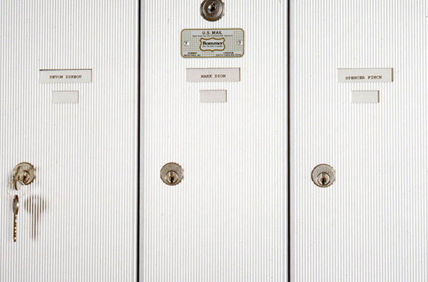 THE MAIL: FANFARE <br/>
1991 Ongoing <br/>
Detail: 1 Station of Apartment Mailboxes Showing the Boxes of Devon Dikeou (with Key), Mark Dion, and Spencer Finch<br/>
Variable Dimensions <br/>