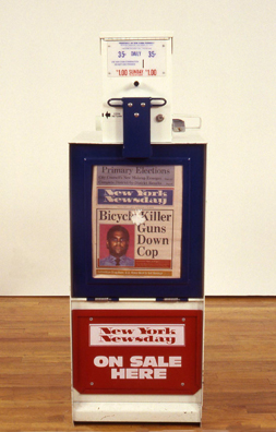 THE NEWS <br/>
1991 Ongoing <br/>
Detail: New York Newsday; “Bicycle Killer Guns Down Cop”<br/>
Fully Operational New York Newsday Dispenser, Available for Viewers to Use for the Duration of the Exhibition, Papers Updated on Daily/Weekly Basis by Appropriate News Agencies <br/>
18” x 49” x 20” Each<br/>