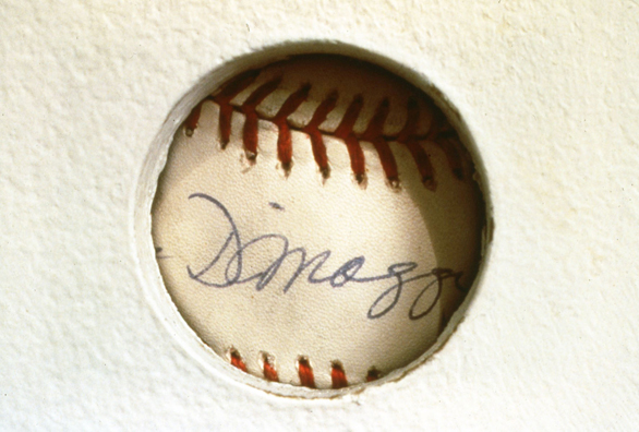 TOUCH OF GREATNESS: JOE DIMAGGIO<br/>
1994 Ongoing <br/>
Detail: Autograph Rotated<br/>
Autographed Baseball from the Artist's Personal Collection: Joe DiMaggio <br/>
Left Unguarded to Rotate Behind “The Hole” and Collection Viewer's Fingerprints, Diminishing in Value as a Collectible, while Increasing in Value as an Art Object <br/>
Dimensions: Regulation American League Baseball <br/>