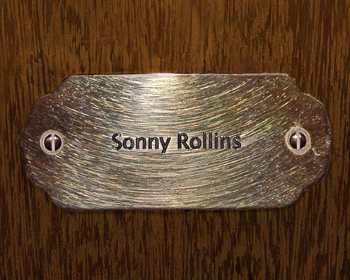 “MAMAS DON'T LET YOUR BABIES GROW UP TO BE COWBOYS”<br/>
Sonny Rollins<br/>
2009 ongoing <br/>
C-Print of a Name Plate Reserving a Hotel Room in Perpetuity for the Tenor/Soprano Jazz Legend, Sonny Rollins<br/>
Mounted on Wood with Non-Glare Plexiglas Surface<br/>
7 3/4” x 9 3/4” x 3/4” <br/>