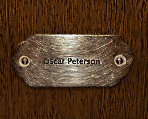 “MAMAS DON'T LET YOUR BABIES GROW UP TO BE COWBOYS”<br/>
Oscar Peterson<br/>
2009 ongoing <br/>
C-Print of a Name Plate Reserving a Hotel Room in Perpetuity for the Piano Jazz Legend, Oscar Peterson<br/>
Mounted on Wood with Non-Glare Plexiglas Surface<br/>
7 3/4” x 9 3/4” x 3/4” <br/>