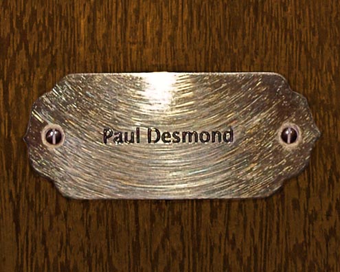 “MAMAS DON'T LET YOUR BABIES GROW UP TO BE COWBOYS”<br/>
Paul Desmond<br/>
2009 ongoing <br/>
C-Print of a Name Plate Reserving a Hotel Room in Perpetuity for the Alto Sax Jazz Legend, Paul Desmond<br/>
Mounted on Wood with Non-Glare Plexiglas Surface<br/>
7 3/4” x 9 3/4” x 3/4” <br/>