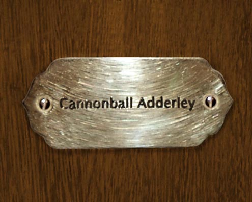 “MAMAS DON'T LET YOUR BABIES GROW UP TO BE COWBOYS”<br/>
Cannonball Adderley<br/>
2009 ongoing <br/>
C-Print of a Name Plate Reserving a Hotel Room in Perpetuity for the Alto/Tenor Sax Jazz Legend, Cannonball Adderley<br/>
Mounted on Wood with Non-Glare Plexiglas Surface<br/>
7 3/4” x 9 3/4” x 3/4” <br/>
