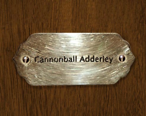 “MAMAS DON'T LET YOUR BABIES GROW UP TO BE COWBOYS”<br/>
Cannonball Adderley<br/>
2009 ongoing <br/>
C-Print of a Name Plate Reserving a Hotel Room in Perpetuity for the Alto/Tenor Sax Jazz Legend, Cannonball Adderley<br/>
Mounted on Wood with Non-Glare Plexiglas Surface<br/>
7 3/4” x 9 3/4” x 3/4” <br/>