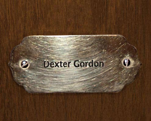 “MAMAS DON'T LET YOUR BABIES GROW UP TO BE COWBOYS”<br/>
Dexter Gordon<br/>
2009 ongoing <br/>
C-Print of a Name Plate Reserving a Hotel Room in Perpetuity for the Tenor Sax Jazz Legend, Dexter Gordon<br/>
Mounted on Wood with Non-Glare Plexiglas Surface<br/>
7 3/4” x 9 3/4” x 3/4” <br/>