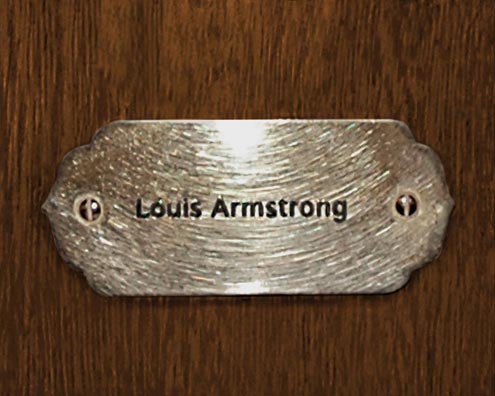 “MAMAS DON'T LET YOUR BABIES GROW UP TO BE COWBOYS”<br/>
Louis Armstrong<br/>
2009 ongoing <br/>
C-Print of a Name Plate Reserving a Hotel Room in Perpetuity for the Trumpet Jazz Legend, Louis Armstrong<br/>
Mounted on Wood with Non-Glare Plexiglas Surface<br/>
7 3/4” x 9 3/4” x 3/4” <br/>