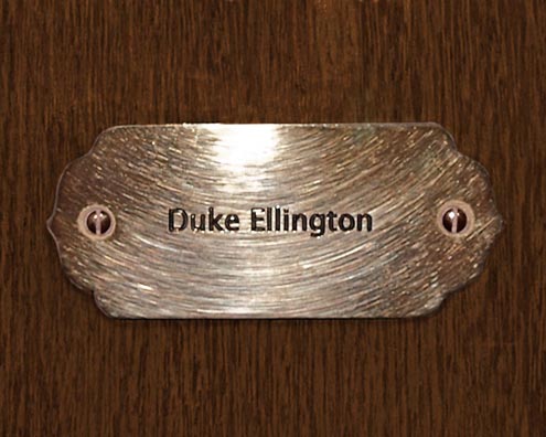“MAMAS DON'T LET YOUR BABIES GROW UP TO BE COWBOYS”<br/>
Duke Ellington<br/>
2009 ongoing <br/>
C-Print of a Name Plate Reserving a Hotel Room in Perpetuity for the Piano Jazz Legend, Duke Ellington<br/>
Mounted on Wood with Non-Glare Plexiglas Surface<br/>
7 3/4” x 9 3/4” x 3/4” <br/>
