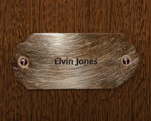 “MAMAS DON'T LET YOUR BABIES GROW UP TO BE COWBOYS”<br/>
Elvin Jones<br/>
2009 ongoing <br/>
C-Print of a Name Plate Reserving a Hotel Room in Perpetuity for the Drums Jazz Legend, Elvin Jones<br/>
Mounted on Wood with Non-Glare Plexiglas Surface<br/>
7 3/4” x 9 3/4” x 3/4” <br/>