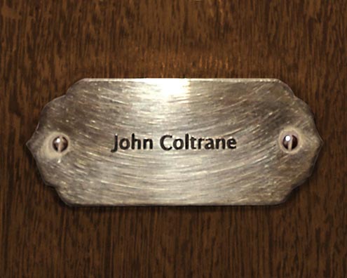 “MAMAS DON'T LET YOUR BABIES GROW UP TO BE COWBOYS”<br/>
John Coltrane<br/>
2009 ongoing <br/>
C-Print of a Name Plate Reserving a Hotel Room in Perpetuity for the Multifarious Jazz Legend, John Coltrane<br/>
Mounted on Wood with Non-Glare Plexiglas Surface<br/>
7 3/4” x 9 3/4” x 3/4” <br/>