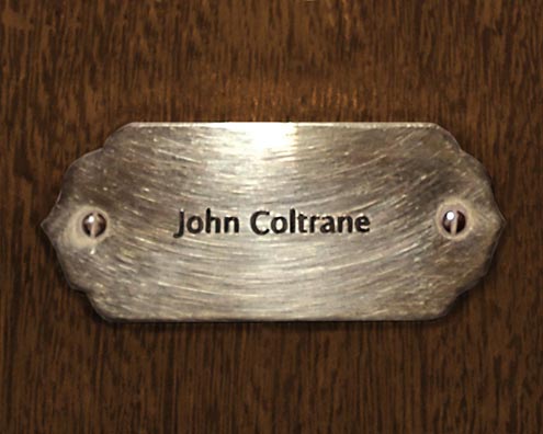 “MAMAS DON'T LET YOUR BABIES GROW UP TO BE COWBOYS”<br/>
John Coltrane<br/>
2009 ongoing <br/>
C-Print of a Name Plate Reserving a Hotel Room in Perpetuity for the Multifarious Jazz Legend, John Coltrane<br/>
Mounted on Wood with Non-Glare Plexiglas Surface<br/>
7 3/4” x 9 3/4” x 3/4” <br/>