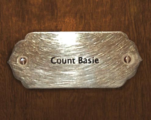 “MAMAS DON'T LET YOUR BABIES GROW UP TO BE COWBOYS”<br/>
Count Basie<br/>
2009 ongoing <br/>
C-Print of a Name Plate Reserving a Hotel Room in Perpetuity for the Piano/Organ Jazz Legend, Count Basie<br/>
Mounted on Wood with Non-Glare Plexiglas Surface<br/>
7 3/4” x 9 3/4” x 3/4” <br/>