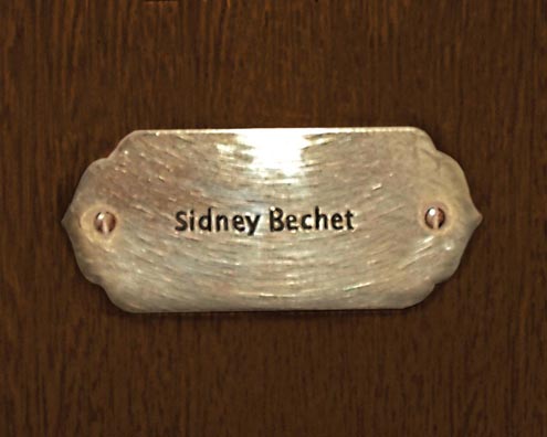 “MAMAS DON'T LET YOUR BABIES GROW UP TO BE COWBOYS”<br/>
Sidney Bechet<br/>
2009 ongoing <br/>
C-Print of a Name Plate Reserving a Hotel Room in Perpetuity for the Sax/Clarinet Jazz Legend, Sidney Bechet<br/>
Mounted on Wood with Non-Glare Plexiglas Surface<br/>
7 3/4” x 9 3/4” x 3/4” <br/>
