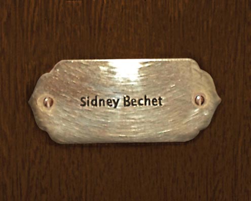 “MAMAS DON'T LET YOUR BABIES GROW UP TO BE COWBOYS”<br/>
Sidney Bechet<br/>
2009 ongoing <br/>
C-Print of a Name Plate Reserving a Hotel Room in Perpetuity for the Sax/Clarinet Jazz Legend, Sidney Bechet<br/>
Mounted on Wood with Non-Glare Plexiglas Surface<br/>
7 3/4” x 9 3/4” x 3/4” <br/>