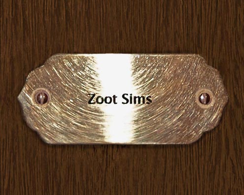 “MAMAS DON'T LET YOUR BABIES GROW UP TO BE COWBOYS”<br/>
Zoot Sims<br/>
2009 ongoing <br/>
C-Print of a Name Plate Reserving a Hotel Room in Perpetuity for the Tenor/Soprano Sax Jazz Legend, Zoot Sims<br/>
Mounted on Wood with Non-Glare Plexiglas Surface<br/>
7 3/4” x 9 3/4” x 3/4” <br/>