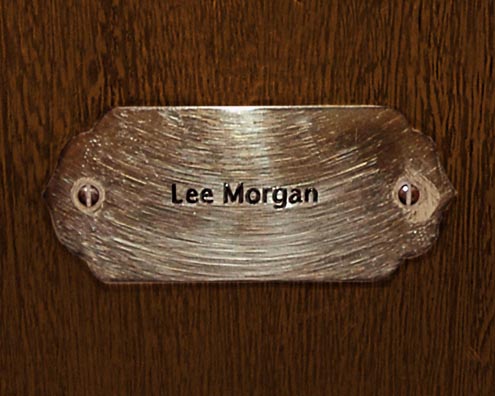 “MAMAS DON'T LET YOUR BABIES GROW UP TO BE COWBOYS”<br/>
Lee Morgan<br/>
2009 ongoing <br/>
C-Print of a Name Plate Reserving a Hotel Room in Perpetuity for the Trumpet Jazz Legend, Lee Morgan<br/>
Mounted on Wood with Non-Glare Plexiglas Surface<br/>
7 3/4” x 9 3/4” x 3/4” <br/>