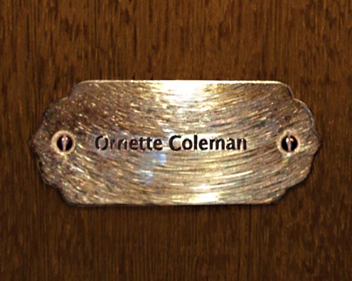 “MAMAS DON'T LET YOUR BABIES GROW UP TO BE COWBOYS”<br/>
Ornette Coleman<br/>
2009 ongoing <br/>
C-Print of a Name Plate Reserving a Hotel Room in Perpetuity for the Multifarious Jazz Legend, Ornette Coleman<br/>
Mounted on Wood with Non-Glare Plexiglas Surface<br/>
7 3/4” x 9 3/4” x 3/4” <br/>