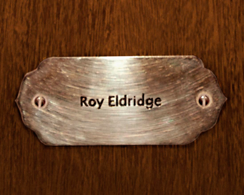 “MAMAS DON'T LET YOUR BABIES GROW UP TO BE COWBOYS”<br/>
Roy Eldridge<br/>
2009 ongoing <br/>
C-Print of a Name Plate Reserving a Hotel Room in Perpetuity for the Trumpet Jazz Legend, Roy Eldridge<br/>
Mounted on Wood with Non-Glare Plexiglas Surface<br/>
7 3/4” x 9 3/4” x 3/4” <br/>