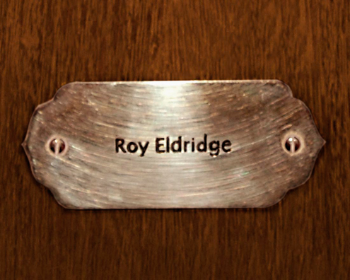 “MAMAS DON'T LET YOUR BABIES GROW UP TO BE COWBOYS”<br/>
Roy Eldridge<br/>
2009 ongoing <br/>
C-Print of a Name Plate Reserving a Hotel Room in Perpetuity for the Trumpet Jazz Legend, Roy Eldridge<br/>
Mounted on Wood with Non-Glare Plexiglas Surface<br/>
7 3/4” x 9 3/4” x 3/4” <br/>