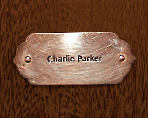 “MAMAS DON'T LET YOUR BABIES GROW UP TO BE COWBOYS”<br/>
Charlie Parker<br/>
2009 ongoing <br/>
C-Print of a Name Plate Reserving a Hotel Room in Perpetuity for the Alto/Tenor Sax Jazz Legend, Charlie Parker<br/>
Mounted on Wood with Non-Glare Plexiglas Surface<br/>
7 3/4” x 9 3/4” x 3/4” <br/>