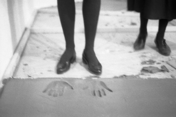 NORMA TALMADGE'S CHINESE THEATER: THE EUROPEAN LEG; KOLN<br />
1992 Ongoing<br />
Happening: Viewer's Immortalizing Themselves by Making Imprints in Fresh Cement in Homage to the Forgotten Silent Diva, Norma Talmadge, the Accidental Auteur of the Canonical Practice<br />
Photograph of Happening Displayed on Wall in Koln Tableau: Philomene Magers and Elizabeth Cherry, “A Broken Spell” (1910)<br />
4” x 6”<br />