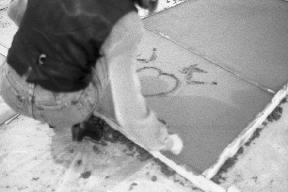 NORMA TALMADGE'S CHINESE THEATER: THE EUROPEAN LEG; KOLN<br />
1992 Ongoing<br />
Happening: Viewer's Immortalizing Themselves by Making Imprints in Fresh Cement in Homage to the Forgotten Silent Diva, Norma Talmadge, the Accidental Auteur of the Canonical Practice<br />
Photograph of Happening Displayed in Collector's Edition Photograph Book: “Kiki” (1926)<br />
4” x 6”<br />