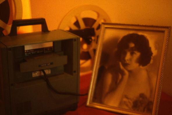 NORMA TALMADGE'S CHINESE THEATER: LA<br />
1992 Ongoing<br />
16 MM Projector, Historic Autographed Photograph of Norma Talmadge, Table, and Table Cloth<br />
Variable Dimensions<br />