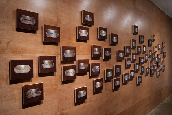 “MAMAS DON'T LET YOUR BABIES GROW UP TO BE COWBOYS”<br/>
2009 ongoing <br/>
Lateral View<br/>
Wall: 56 C-Prints of Name Plates Reserving Hotel Rooms in Perpetuity for 56 Jazz Legends Mounted on Wood with Non-Glare Plexiglas Surface and Installed on a Wall of Wood Paneling<br/>
C-Prints: 7 3/4” x 9 3/4” x 3/4” Each<br/>