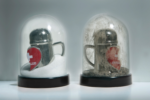 SHAKE: AN ACCUMULATED GIFT COLLECTION OF SALT AND PEPPER SHAKERS <br/>
1991 Ongoing <br/>
Detail: Gift of Charito Troya Traves (Swiss Souvenir Broken Heart Beer Stein Shakers)<br/>
Snow Globes Altered to Become Functioning Salt and Pepper Shakers, Each Filled with Salt and Pepper, and when Used, the Diminishing Salt and Pepper Reveals the Actual Accumulated Gift Collection of Shakers<br/>
3 1/2”H x 2 1/2” in Diameter<br/>