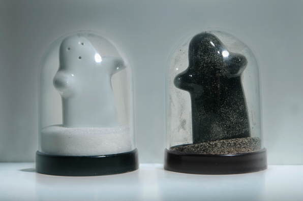 SHAKE: AN ACCUMULATED GIFT COLLECTION OF SALT AND PEPPER SHAKERS <br/>
1991 Ongoing <br/>
Detail: Unknown Gift (Black and White Hugging Ghosts Shakers)<br/>
Snow Globes Altered to Become Functioning Salt and Pepper Shakers, Each Filled with Salt and Pepper, and when Used, the Diminishing Salt and Pepper Reveals the Actual Accumulated Gift Collection of Shakers<br/>
3 1/2”H x 2 1/2” in Diameter<br/>